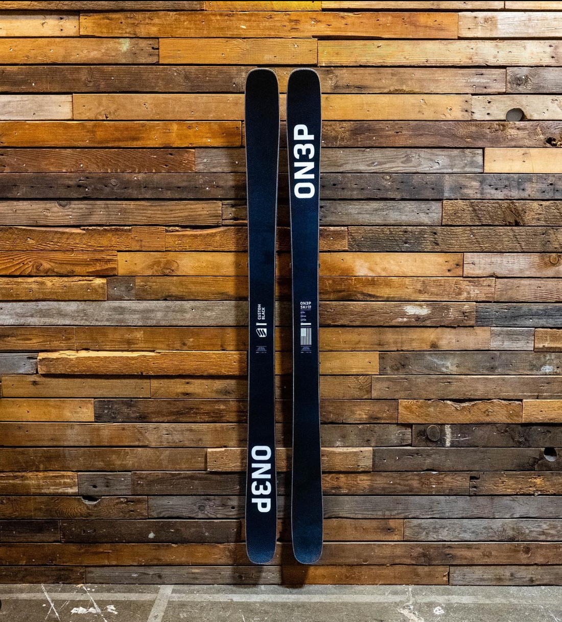 Black ON3P Skis with White Accents on Rustic Wood Wall: Industrial Chic Storage