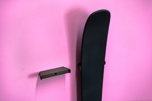 Sleek Black Skis on Vibrant Pink Wall: Minimalist Storage Redefined
