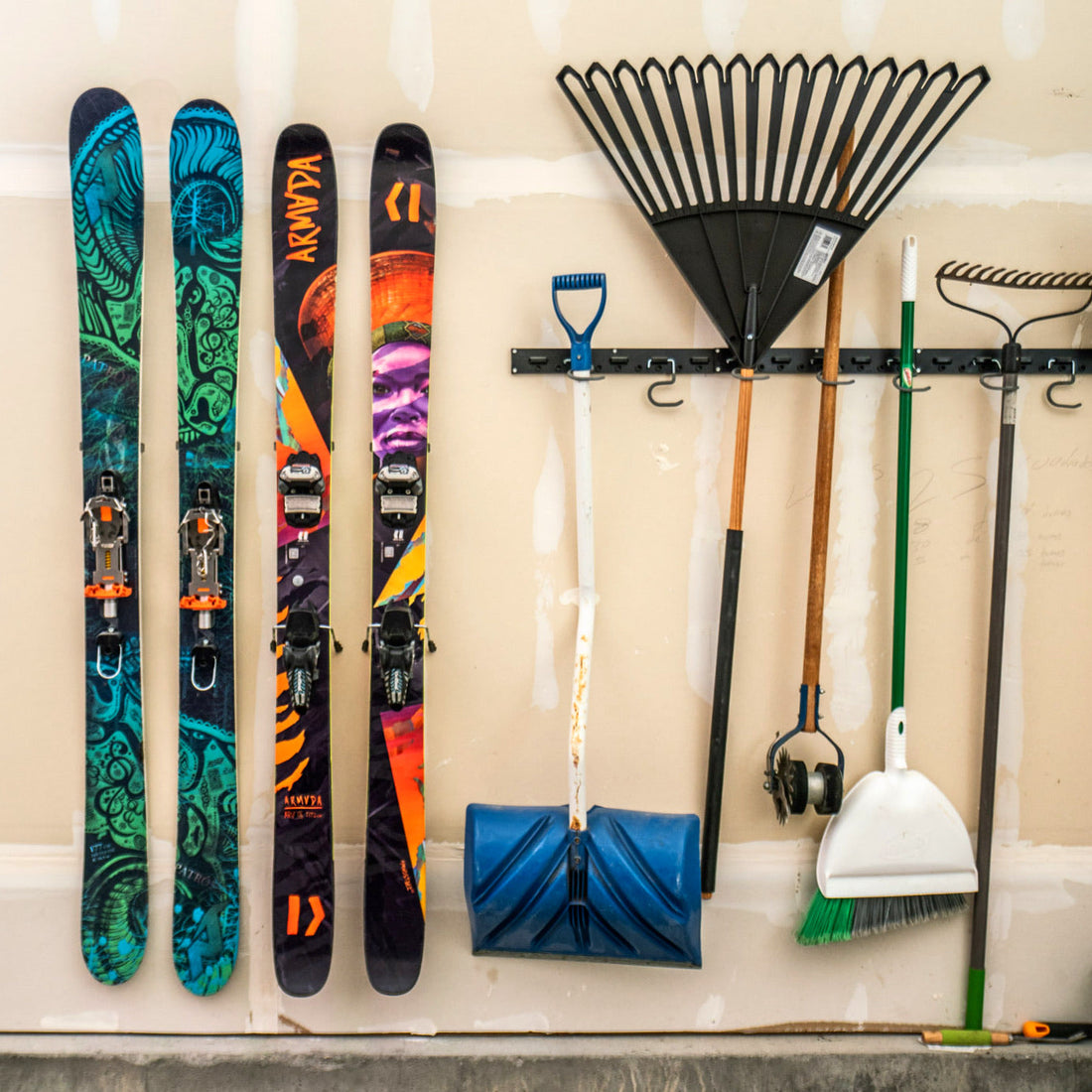 Vibrant Armada Skis with Multicolor Graphics on Beige Wall: Functional Art in Storage
