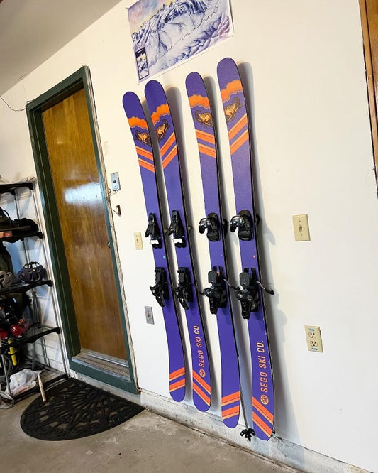 Vibrant Sego Ski Co. Purple and Orange Skis on Modern White Wall Display